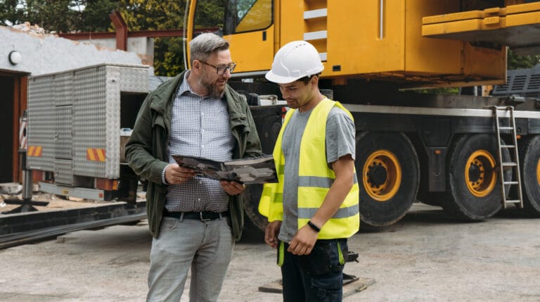 Profissional conversa com cliente ao lado de uma máquina de construção
